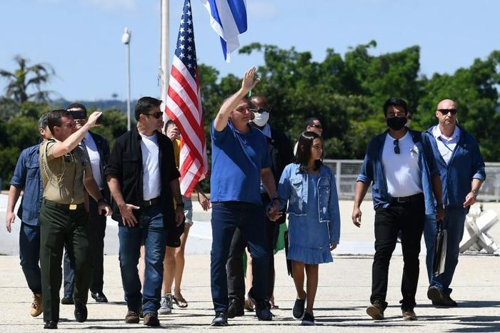 Brazilian President Jair Bolsonaro (C), holding his daughter Laura's hand, waves at supporters gathering outside Planalto Palace in Brasilia, on May 3, 2020