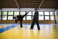 Side view of two men in black kimono practicing hapkido fighting att