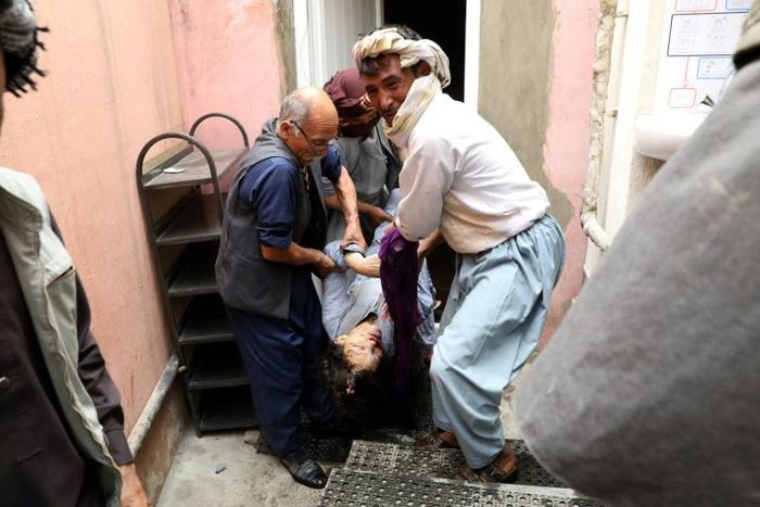 Men carry the dead body of a woman following a suicide attack on a maternity hospital in Kabul