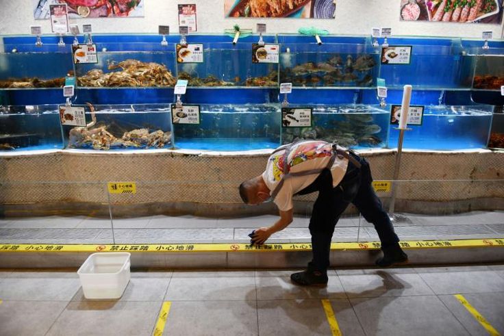 A worker cleans glass in the seafood section of a supermarket in Beijing, where a fresh coronavirus outbreak is keeping customers away
