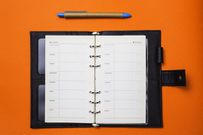 Directly Above Shot Of Open Diary And Book Over Orange Background