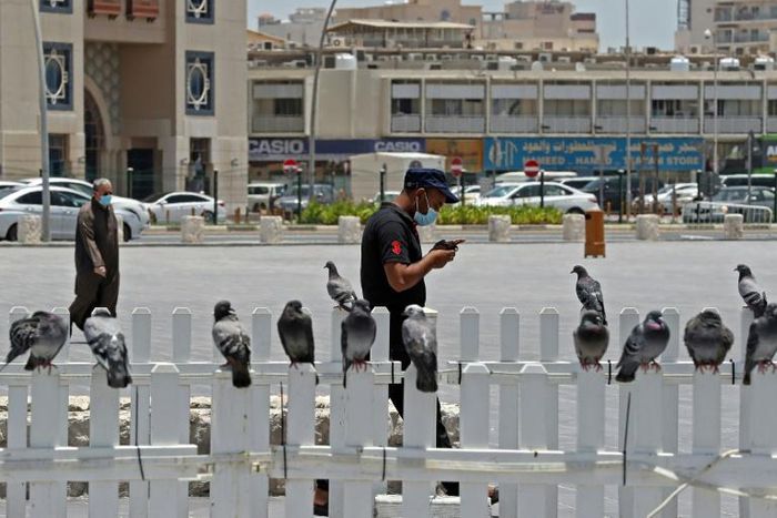 A masked man checks his phone in Qatar where residents and citizens have been required by law to install a coronavirus contact tracing app on their handsets since Friday