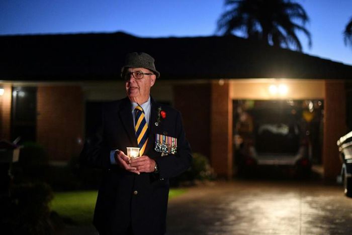 Veteran Peter McFarlane holds a candle during an Anzac Day dawn vigil outside his house in suburbs of Sydney