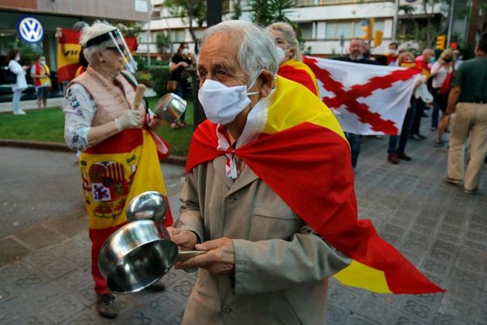 Demonstrators wrapped in Spanish flags protest at what rightwing parties have dubbed a "brutal confinement" after a fifth state of emergency extension
