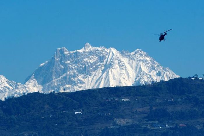 A helicopter carrying a rescue team flies in front of the Annapurna mountain range, in Pokhara, west of Kathmandu, during the initial search in January