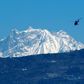 A helicopter carrying a rescue team flies in front of the Annapurna mountain range, in Pokhara, west of Kathmandu, during the initial search in January