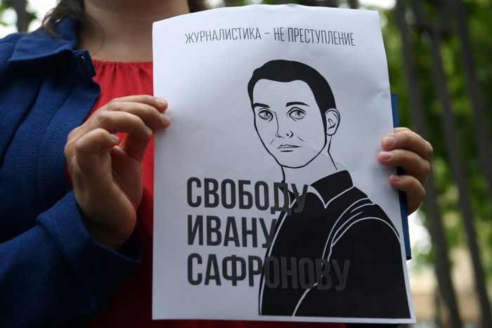 A woman holds a poster featuring an image of Ivan Safronov and the words "Journalism is not a crime"