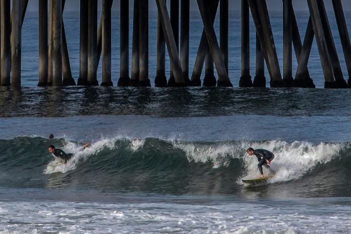 Surfers catch a wave in Huntington Beach, California on May 2