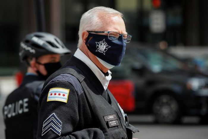 Coronavirus lockdown has hardly made a dent in the homicide rate in Chicago, where an officer is pictured monitoring a car caravan protest on May 7