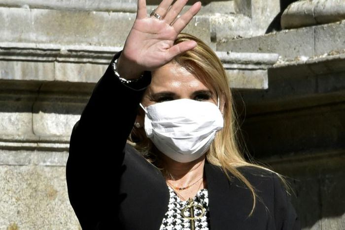 Bolivian interim President Jeanine Anez waves, while wearing a face mask, after attending a Corpus Christi procession at the Plaza de Armas in front of the government palace in La Paz, on June 11, 2020, amid the COVID-19 coronavirus pandemic