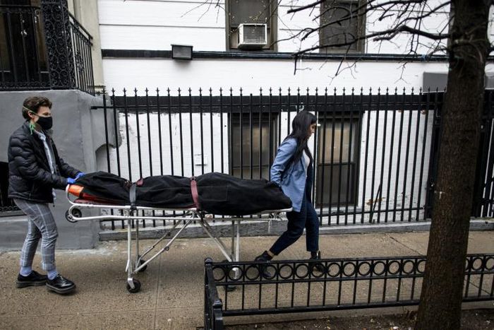 Alisha Narvaez (R) and Lily Sage Weinrieb of International Funeral & Cremation Services transport a body on April 24 in the Harlem neighborhood of New York