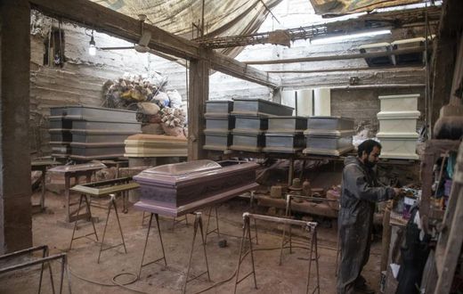 A worker prepares to paint a coffin at a factory in Lima's  Juan de Lurigancho district