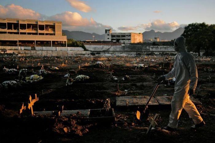 A funeral worker wearing protective clothing as a preventive measure against the coronavirus walks through Caju Cemetary in Rio de Janeiro on May 9