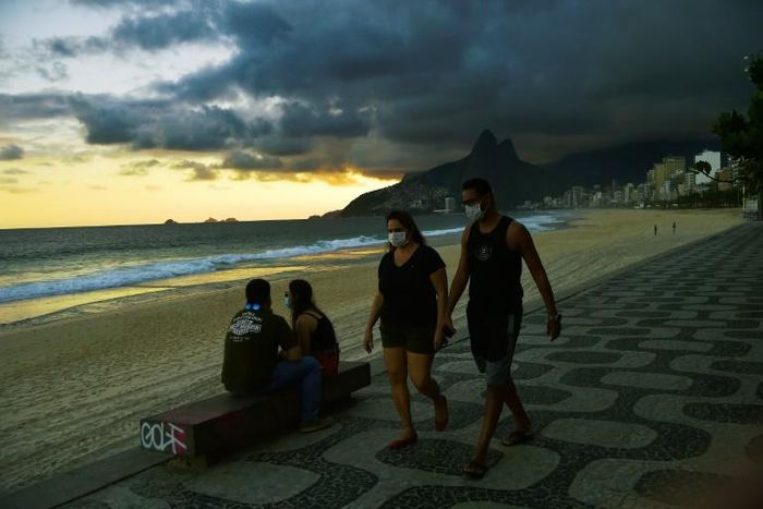 People wear face masks as they walk along Ipanema Beach in Rio de Janeiro on May 19, 2020. The peak of Brazil's outbreak is not expected until June