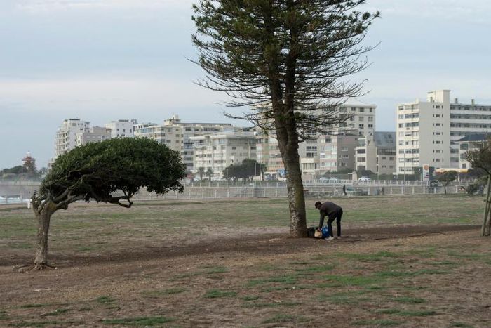 A homeless man stands with some of his belongings at a usually busy promenade in Capetown, now mostly deserted because of the coronavirus lockdown