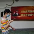 A woman in the original coronavirus epicenter of Wuhan walks in May 2020 past a picture of Chinese President Xi Jinping, who faced rare open domestic criticism over his virus response from a professor who has since been detained