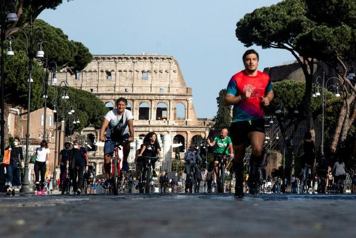 People exercise along Via dei Fori Imperiali in central Rome as Italy begins the careful process of easing its virus lockdown