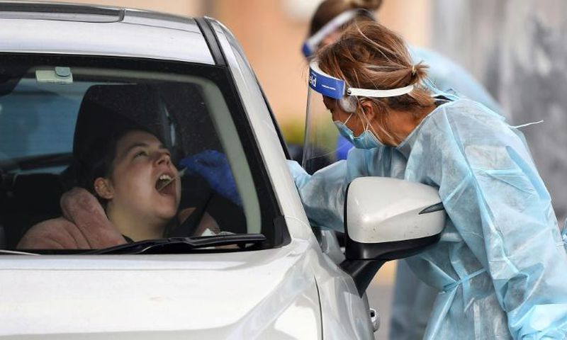 A coronavirus tester takes a swab sample at a drive-through testing station in Melbourne
