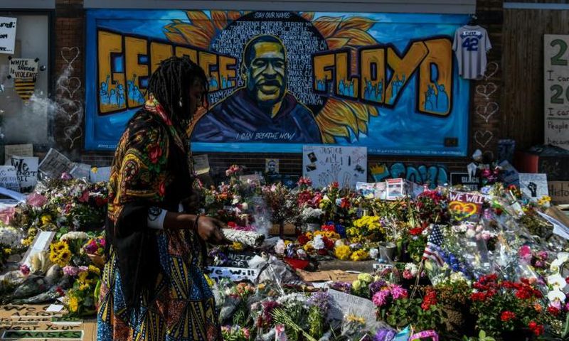 A woman burns sage and offers prayers as she pays her respects at a makeshift memorial in honor of George Floyd, who died while in police custody on May 25