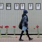 A woman walks past a makeshift memorial for Russian medical workers who have died from the COVID-19 disease, set up outside the local health department in Saint Petersburg. More than 70 have died so far.