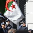 Algerian police wearing face masks stand as protesters march past during an anti-government demonstration in the capital Algiers on March 6