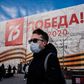 A man wearing a face mask against the spread of the coronavirus walks past a banner for the now much reduced 75th anniversary celebrations in Moscow marking  the victory over Nazi Germany in World War II