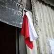 A woman hangs colored flags on the door of her house to signal she needs to be delivered food (white) and medicine (red) for her sick husband, at La Brigada neighbourhood in Guatemala City