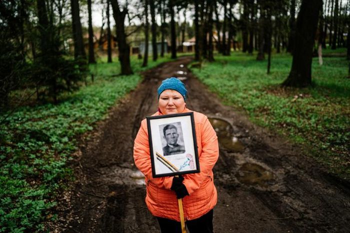 A woman carries a portrait of her grandfather near a monument in a small village outside Moscow dedicated to those who fought in World War II