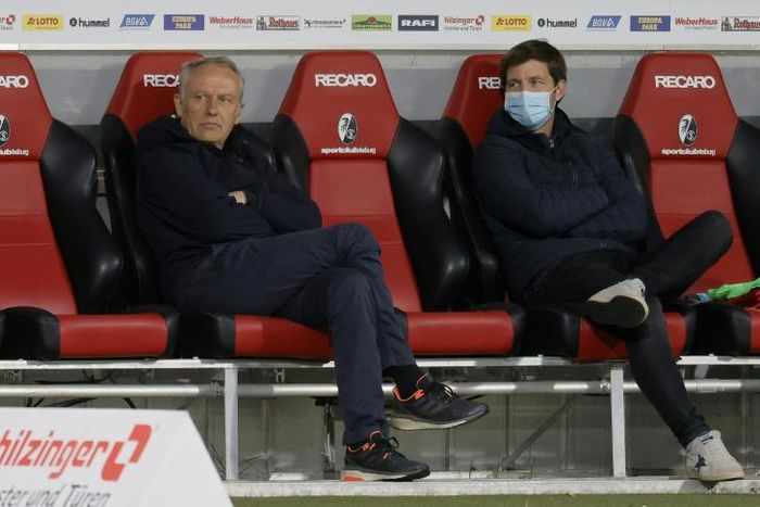 Waiting game: Freiburg coach Christian Streich (left) sits on the bench prior to Friday's game