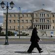 A woman wearing a face mask walks past the empty Syntagma Square in Athens, in front of the Greek Parliament early during the outbreak of COVID-91.
