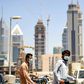 Foreign workers clad in masks to protect against coronavirus push bicycles along a street in the Satwa district of Dubai