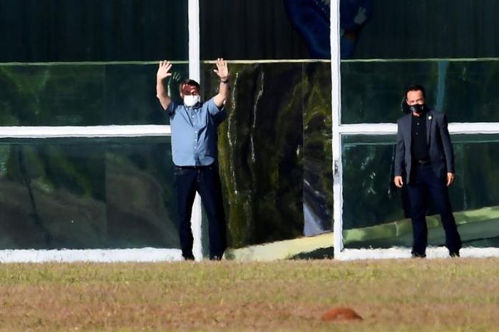 Brazilian President Jair Bolsonaro waves outside Alvorada Palace in Brasilia on July 9, 2020