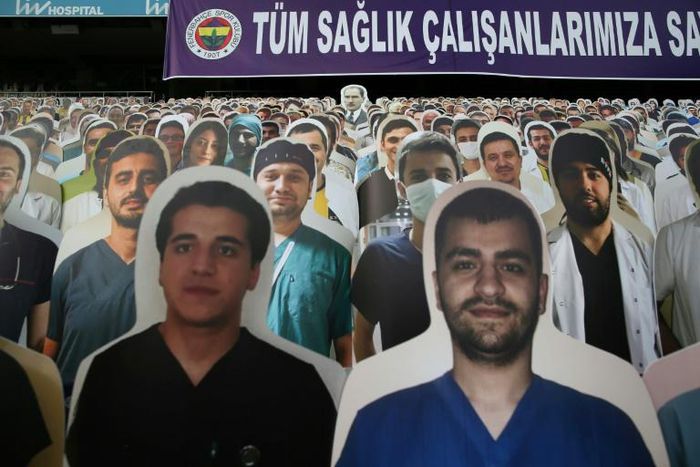 Faces in the crowd: Cardboard cut outs with one picture of Mustafa Kemal Ataturk (back-C), founder of modern Turkey, and photographs of medical staff in front of a banner reading on 'To all our medical staff with respect and gratitude' during the match...