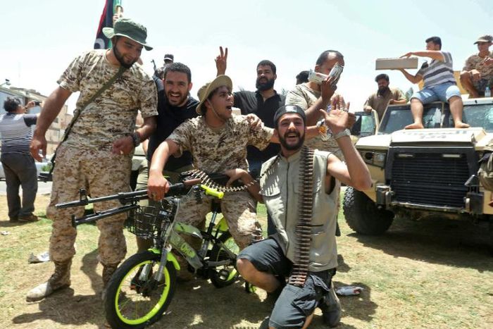 Fighters loyal to Libya's UN-recognised Government of National Accord pose for a picture with a children's bicycle  as they celebrate the capture of the town of Tarhuna, about 65 kilometres southeast of the capital Tripoli