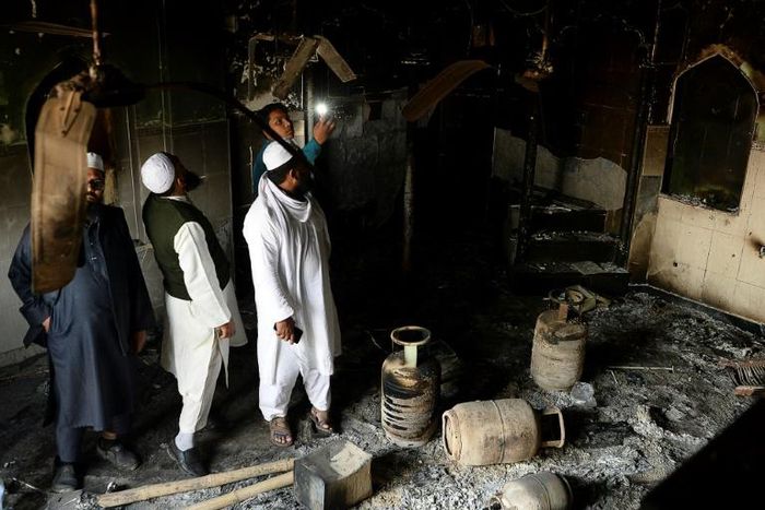 Muslim men check the interior of a partially burnt mosque on March 1, 2020 after communal riots in New Delhi