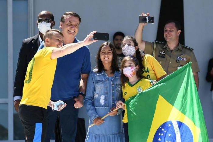 Brazilian President Jair Bolsonaro and his daughter Laura (C) pose for a selfie with supporters outside his residence in Brasilia on Sunday