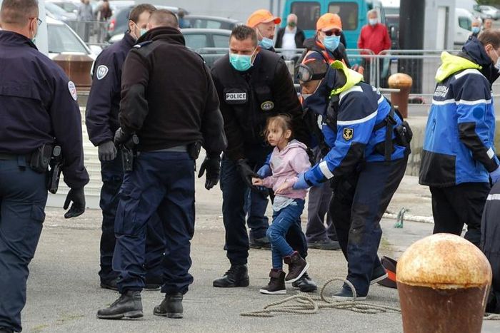 French police, wearing protective masks against the coronavirus, with young migrants picked up off Calais as they tried to get to Britain by boat