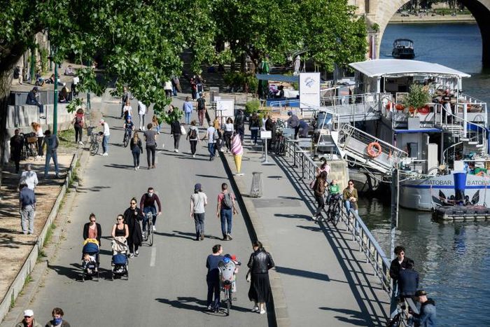 People walk on the banks of the Seine River in Paris on May 15 as France eases lockdown measures taken to curb the spread of the COVID-19 pandemic