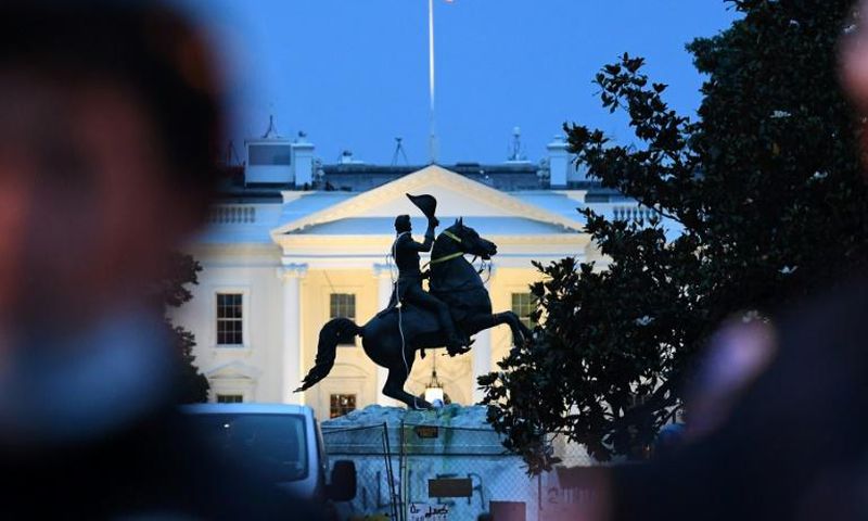 Police officers guard the statue of former US President Andrew Jackson just outside the White House after protesters tried to topple it