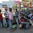 Migrant workers and their families wait for transport back to their home towns