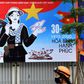 A woman walks next to a hoarding marking the 45th anniversary of the fall of Saigon, in Hanoi