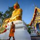 A monk walks in front of a giant Buddha statue wearing a face mask at Wat Nithet Rat Pradit temple in Pathum Thani outside Bangkok