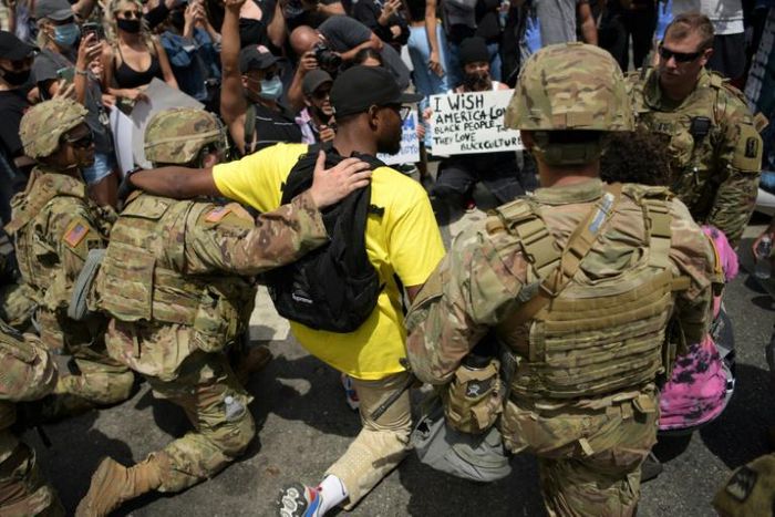 Protesters and members of the Army National Guard kneel together in Los Angeles on June 2, 2020 during a demonstration over the killing of George Floyd