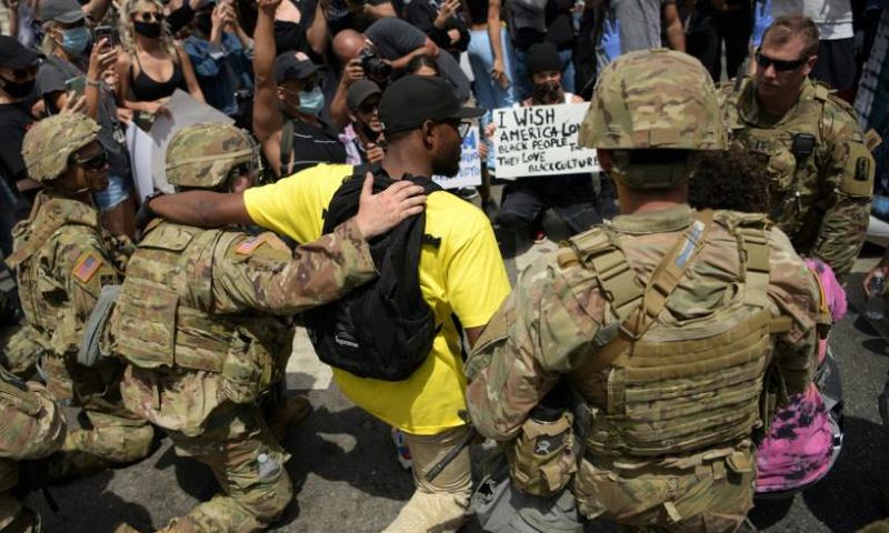 Protesters and members of the Army National Guard kneel together in Los Angeles on June 2, 2020 during a demonstration over the killing of George Floyd
