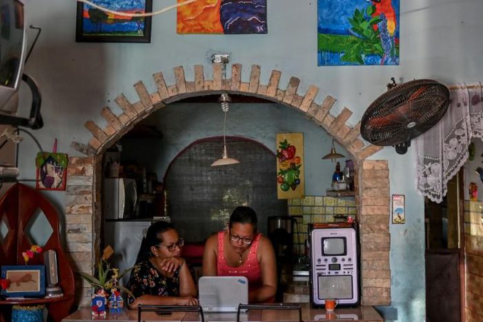 Ana Arias (R), 40, mother of Luisannys Betancourt, who disappeared in a shipwreck en route from Venezuela to Trinidad and Tobago on April 23, 2019, looks for pictures of her daughter in a computer  at her house in Cumana, Sucre State, Venezuela