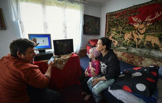 Lucian Cojocaru, a volunteer from "Casa Buna" (The Good Home) NGO, shows a Romanian schoolgirl and her mother how to use a desktop computer, aiding their access to home schooling during the pandemic