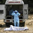 A Muslim man in protective gear offers funeral prayers for a policeman who died from COVID-19 at a graveyard in New Delhi