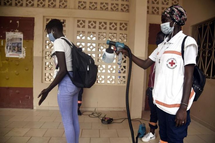 Back to class: A Red Cross worker sprays a pupil with disinfectant at the entrance of a school in Dakar
