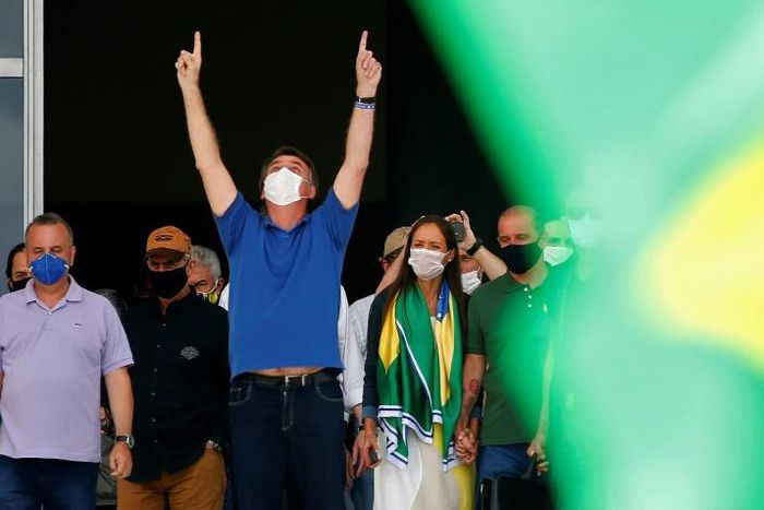 Brazilian President Jair Bolsonaro (C) compares the coronavirus to a "little flu," condemns the "hysteria" surrounding it and is urging the country to get back to work to stop an economic crash