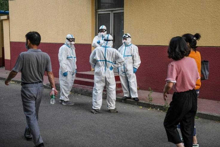 Medical workers in protective equipment take a break at a testing centre for COVID-19 in Beijing this week after a new outbreak whch is also casting fresh doubts over the suspended Chinese Super League football season